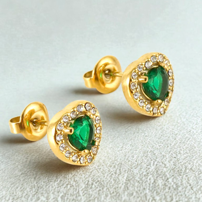 Gold earrings with green gemstones on a light gray background