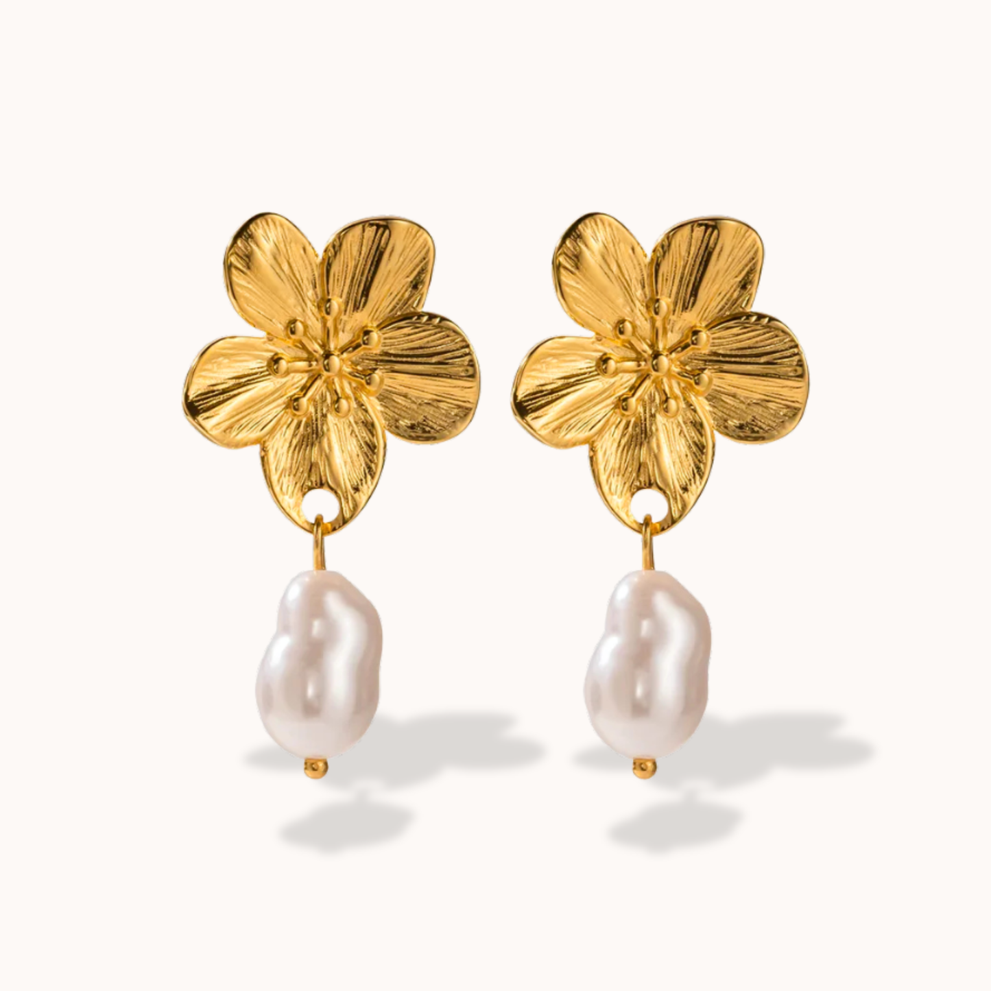 Gold flower-shaped earrings with pearl drops on a white background