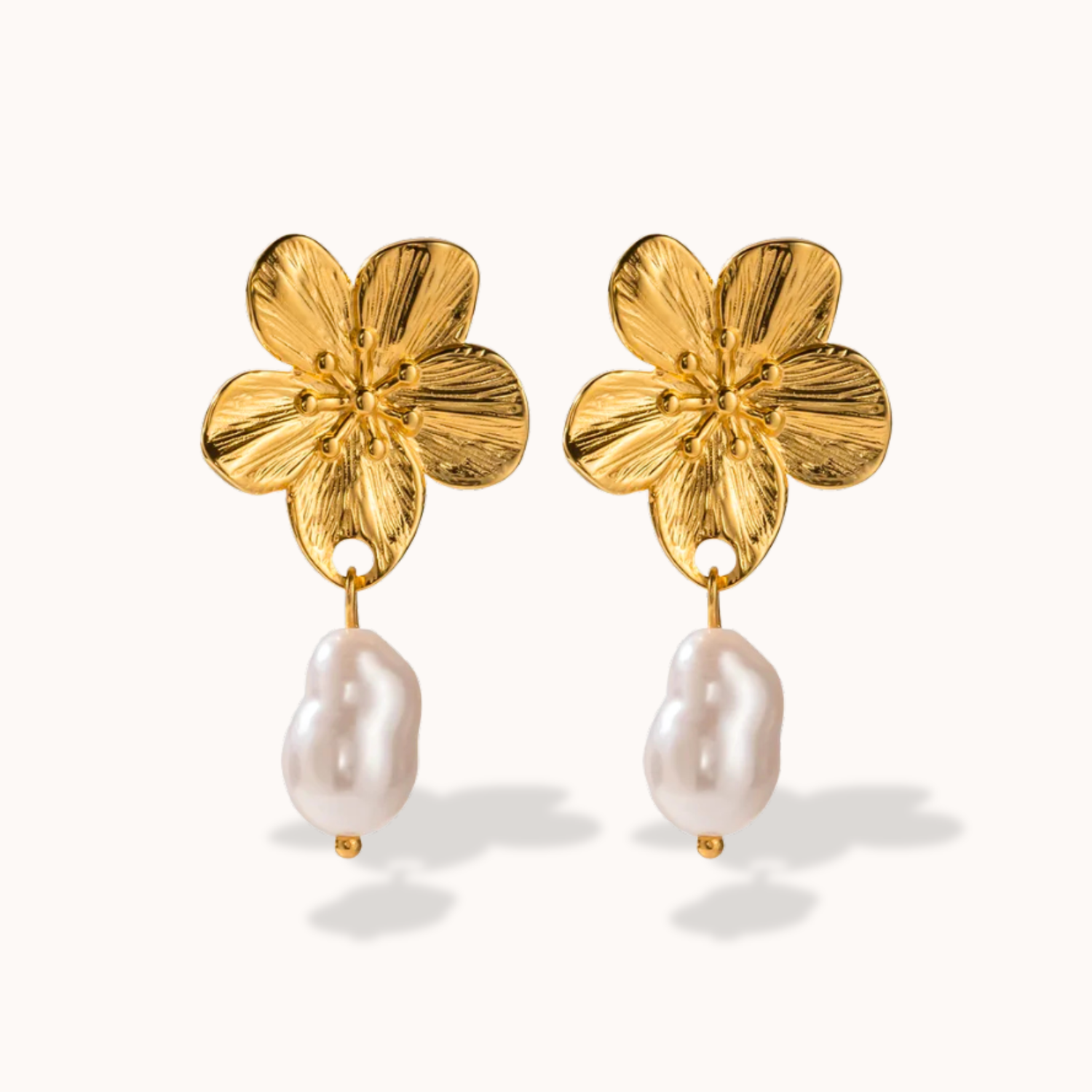 Gold flower-shaped earrings with pearl drops on a white background