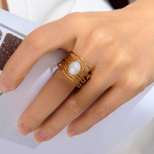 Gold ring with a central pearl on a hand against a white background