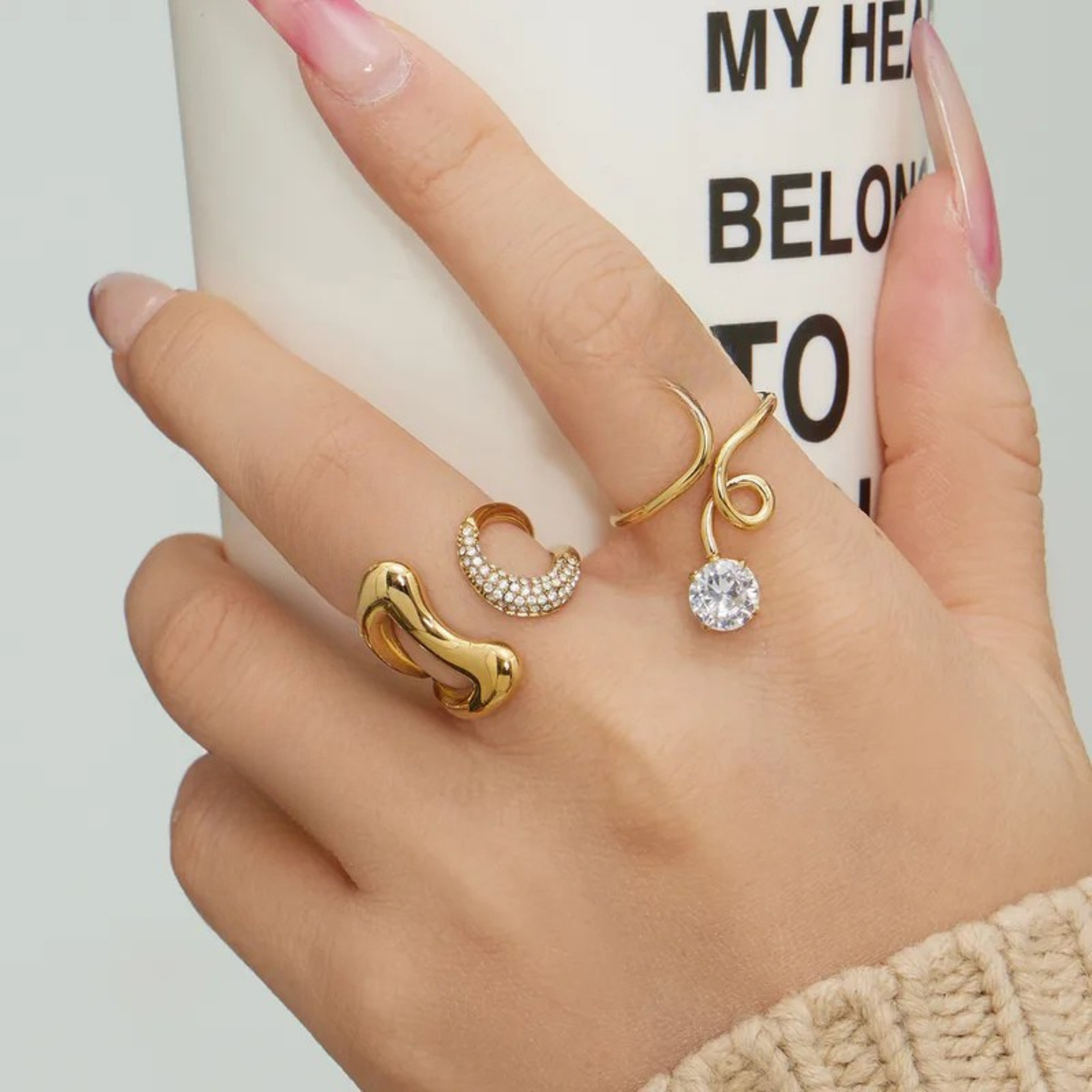 Hand wearing multiple gold rings with a blurred background
