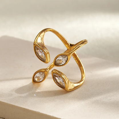 Gold ring with three diamond-like stones on a beige background