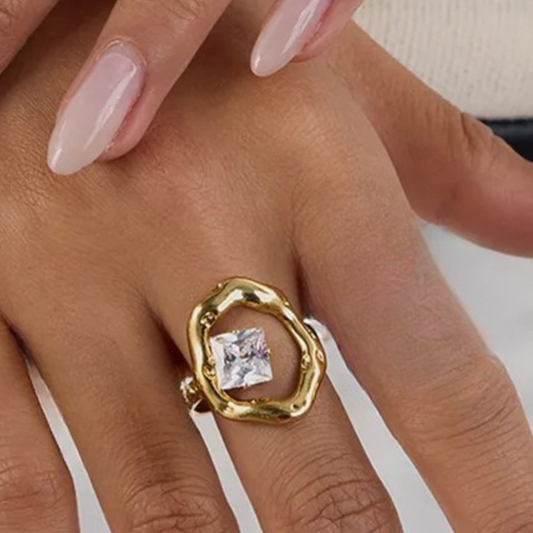 Gold ring with a diamond on a hand against a neutral background