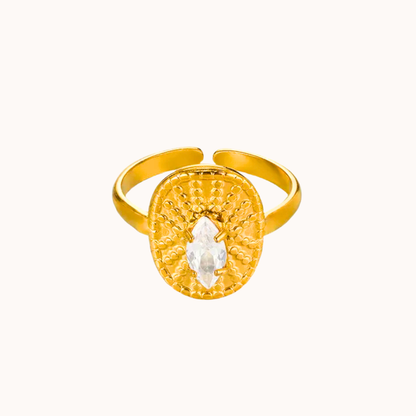 Gold ring with a circular design and central gemstone on a white background