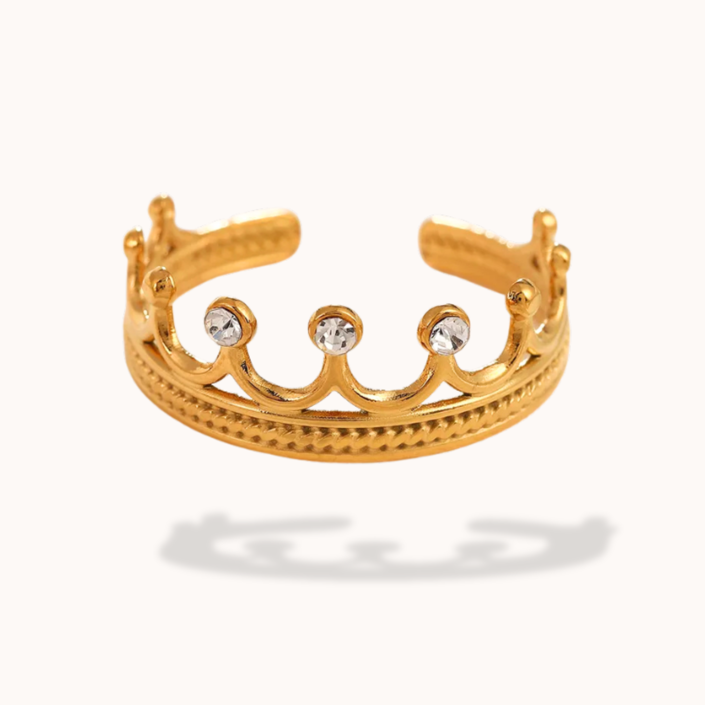 Gold tiara-shaped ring with three clear stones on a white background
