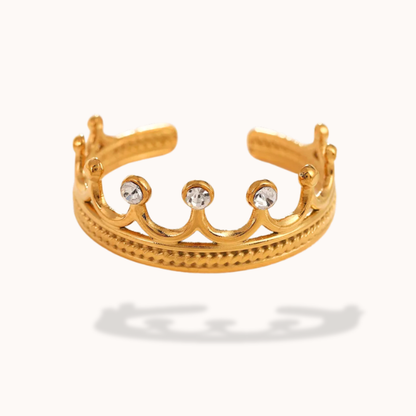 Gold tiara-shaped ring with three clear stones on a white background