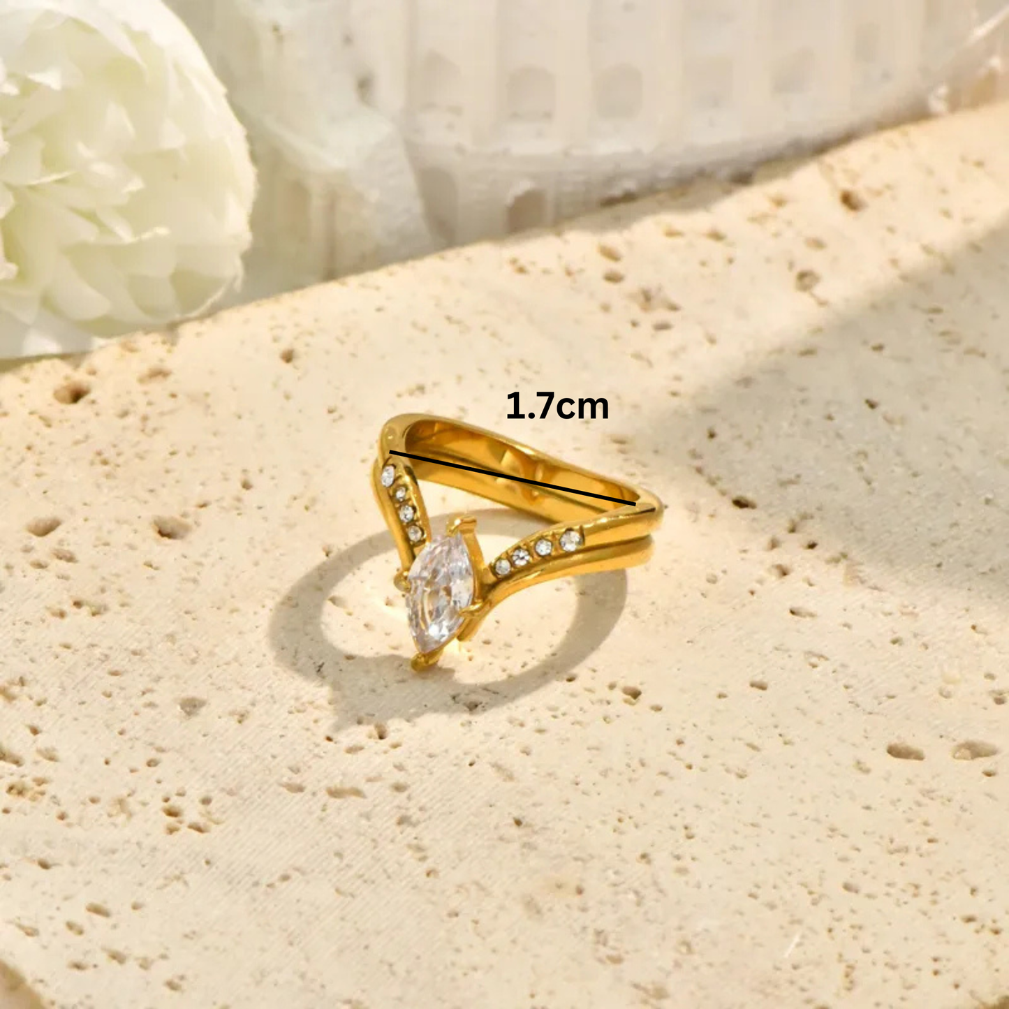 Gold ring with a diamond on a textured beige surface, measurement '1.6cm' displayed.