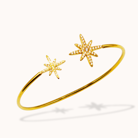 Gold bracelet with star-shaped ends on a white background