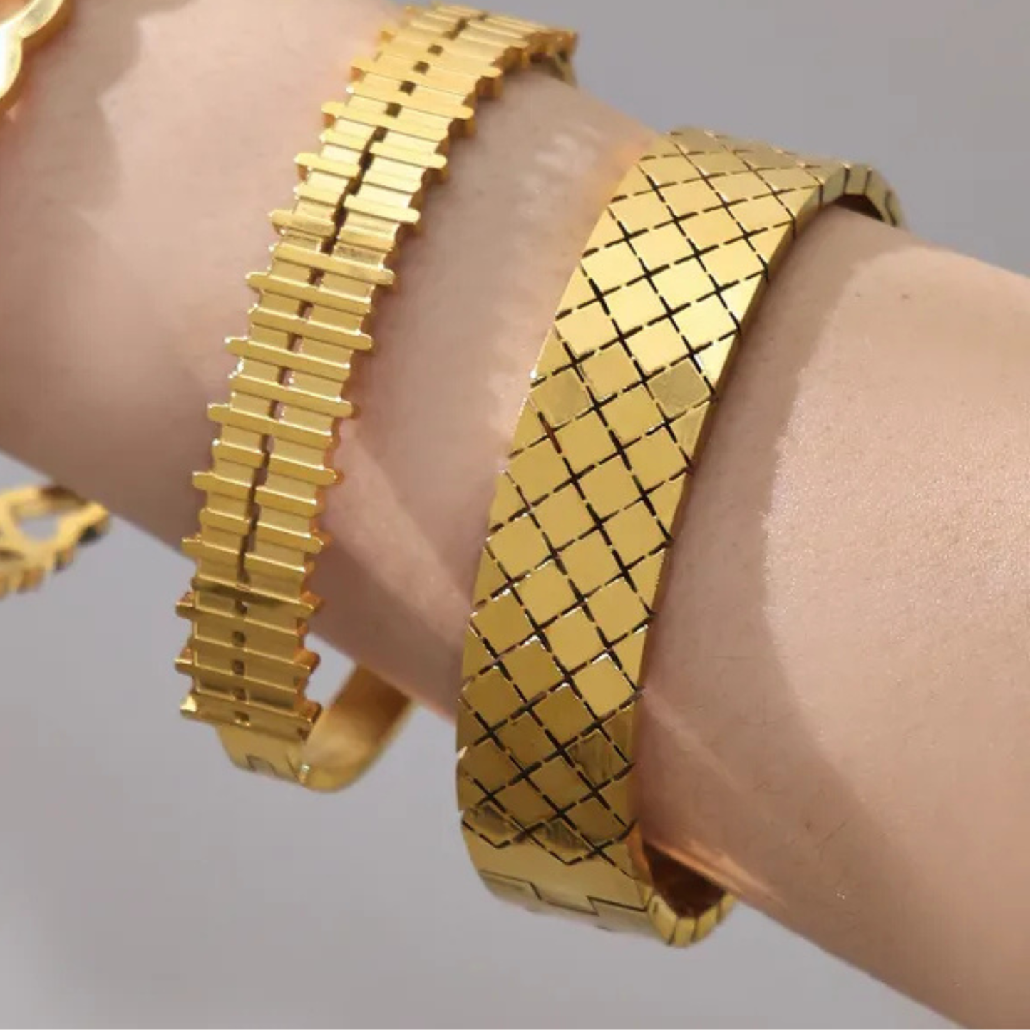 Gold bracelet on a wrist against a neutral background
