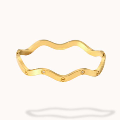 Gold bracelet with wavy design on a white background