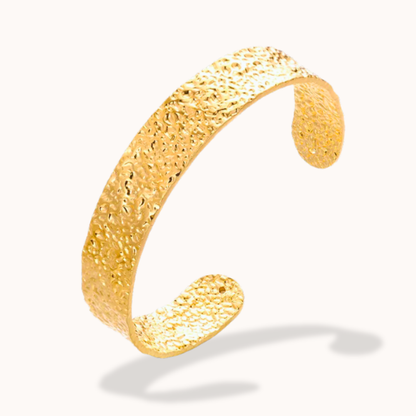 Gold textured bracelet on a white background