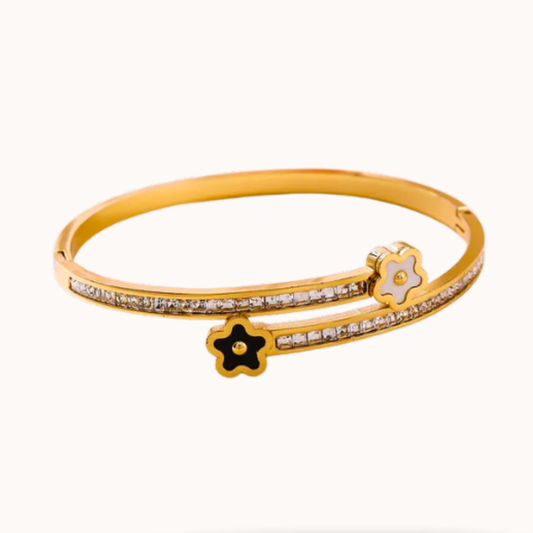 Gold bracelet with star and flower designs on a white background