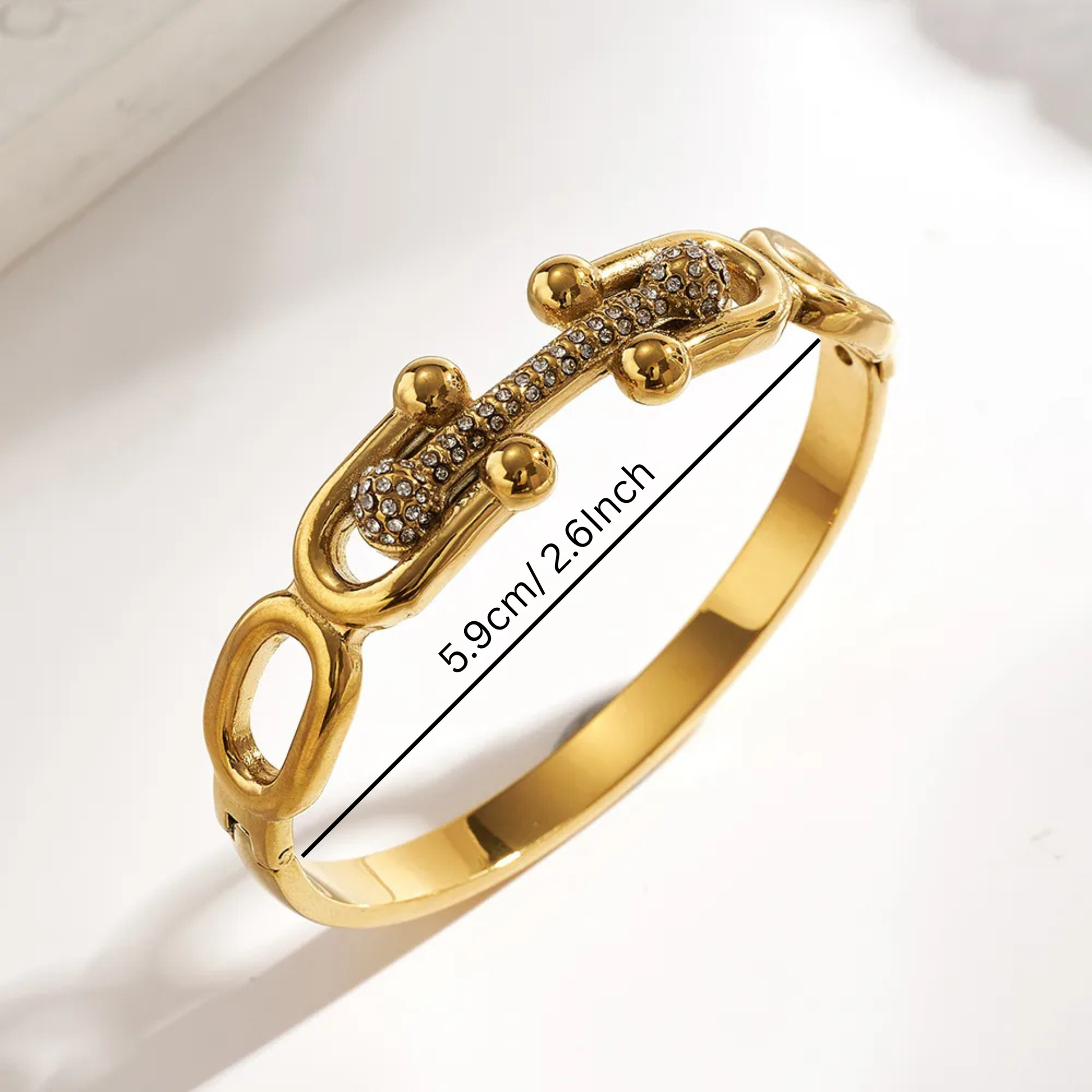 Gold bracelet with intricate design on a light background