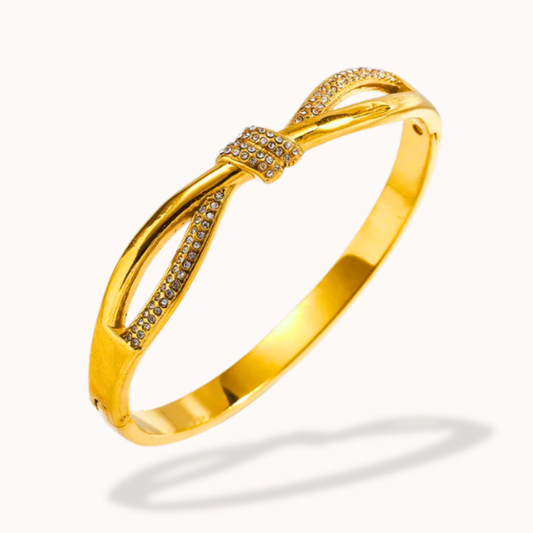 Gold bracelet with bow design on a white background