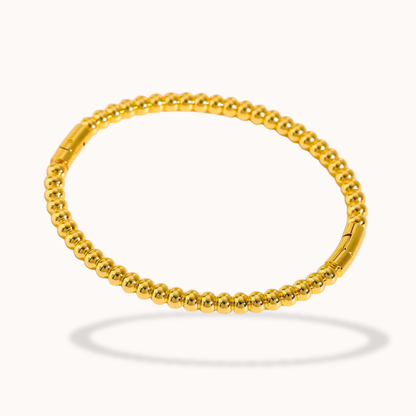 Gold beaded bracelet on a white background