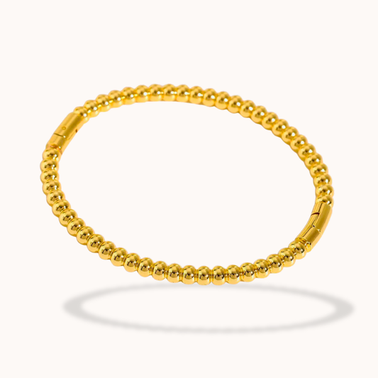 Gold beaded bracelet on a white background
