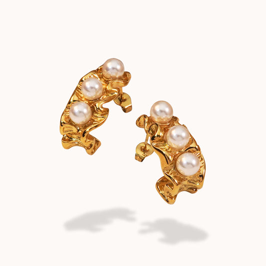 Gold earrings with pearl accents on a white background