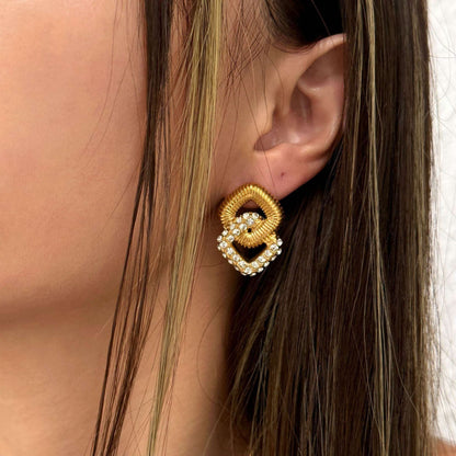 Close-up of a person wearing gold earrings with intricate designs.