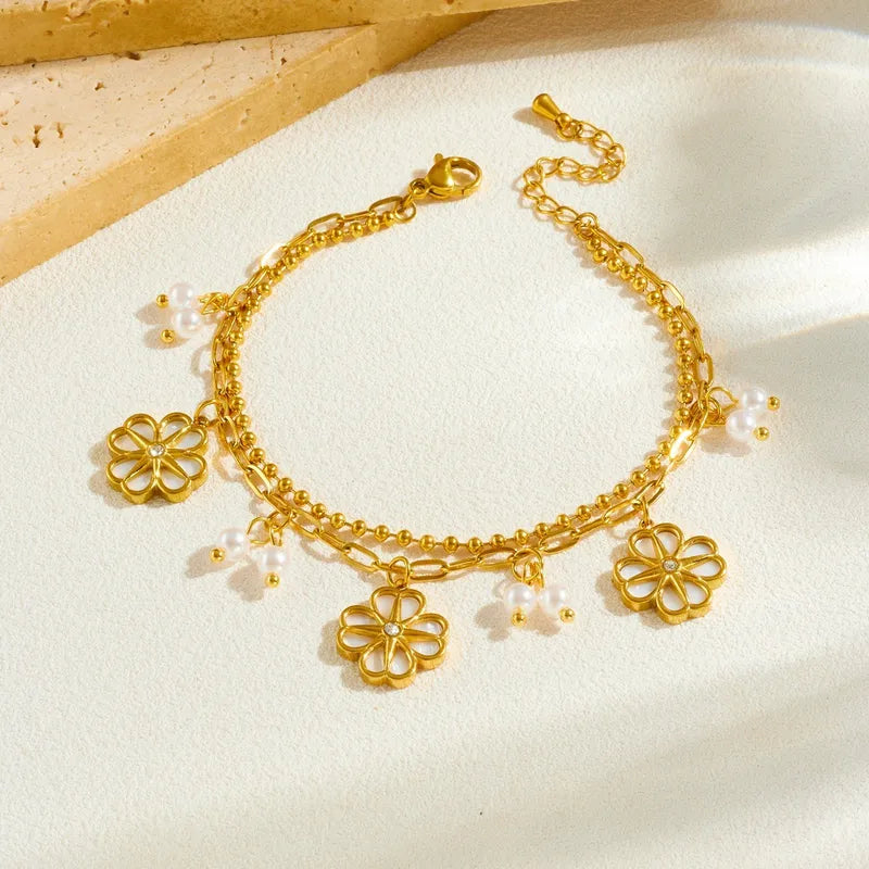 Gold bracelet with floral charms on a light background