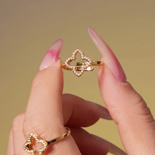 Close-up of a hand holding a gold ring with a star-shaped design against a yellow background