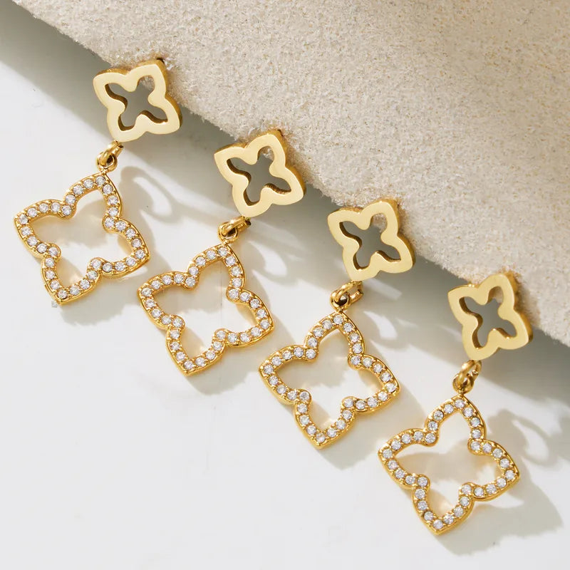 Gold butterfly-shaped earrings with clear stones on a light background