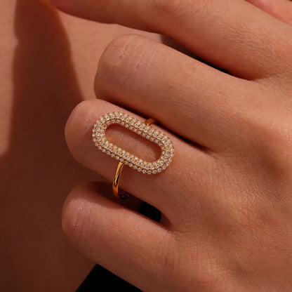 Gold ring with diamonds on a hand against a neutral background