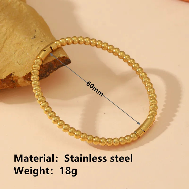 Gold beaded bracelet with measurement details on a beige background