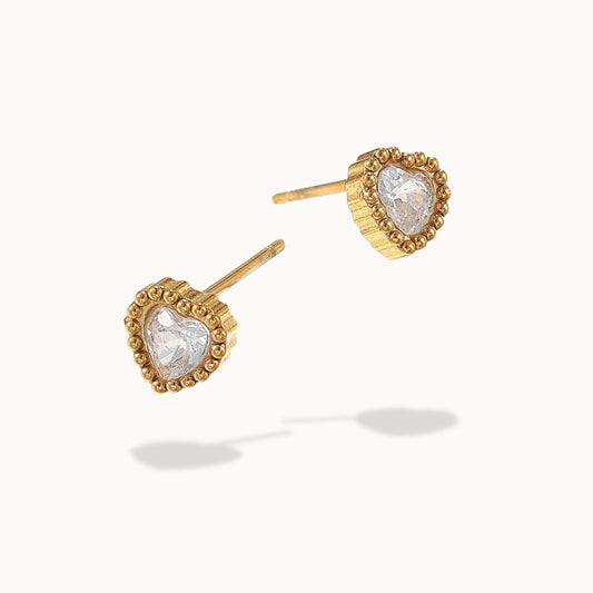 Gold heart-shaped earrings with clear gemstones on a white background
