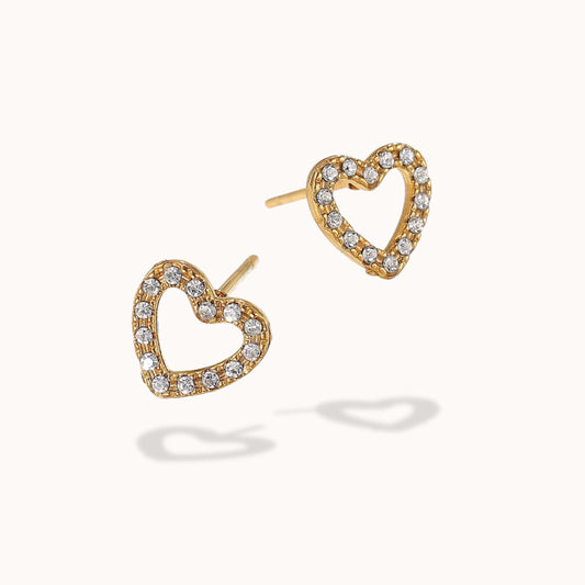 Heart-shaped gold earrings with clear gemstones on a white background