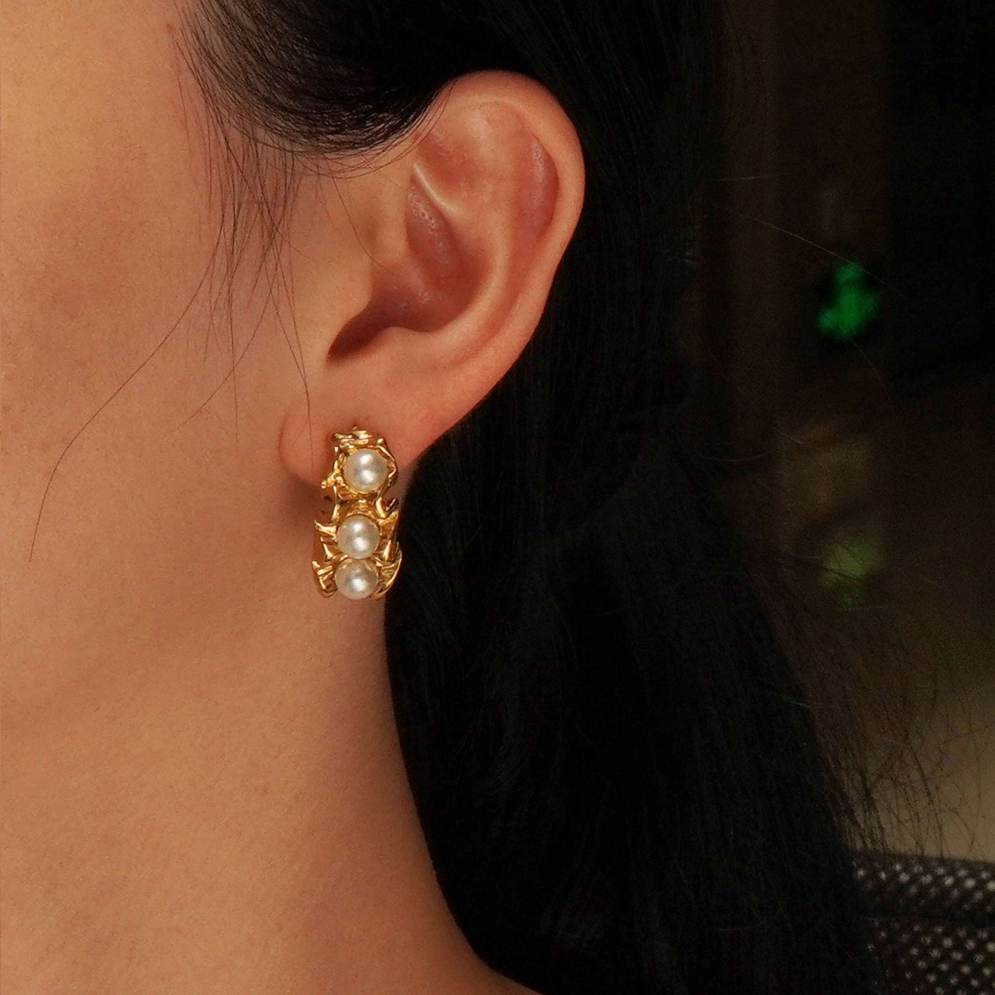 Gold earring with pearls worn by a person