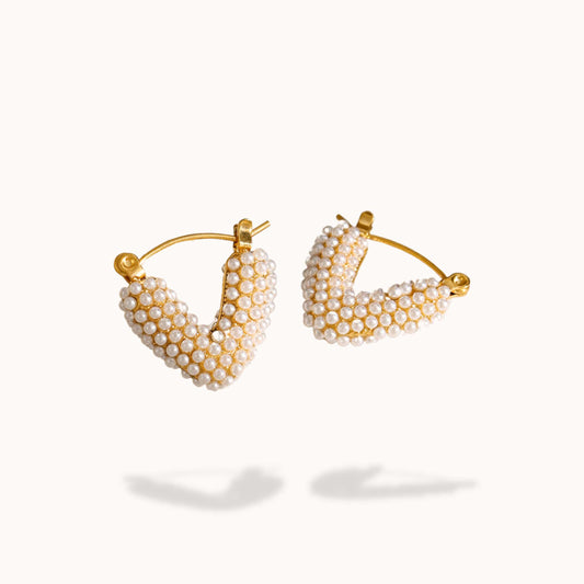 Gold hoop earrings with pearl beads on a white background