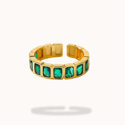 Gold ring with green gemstones on a white background