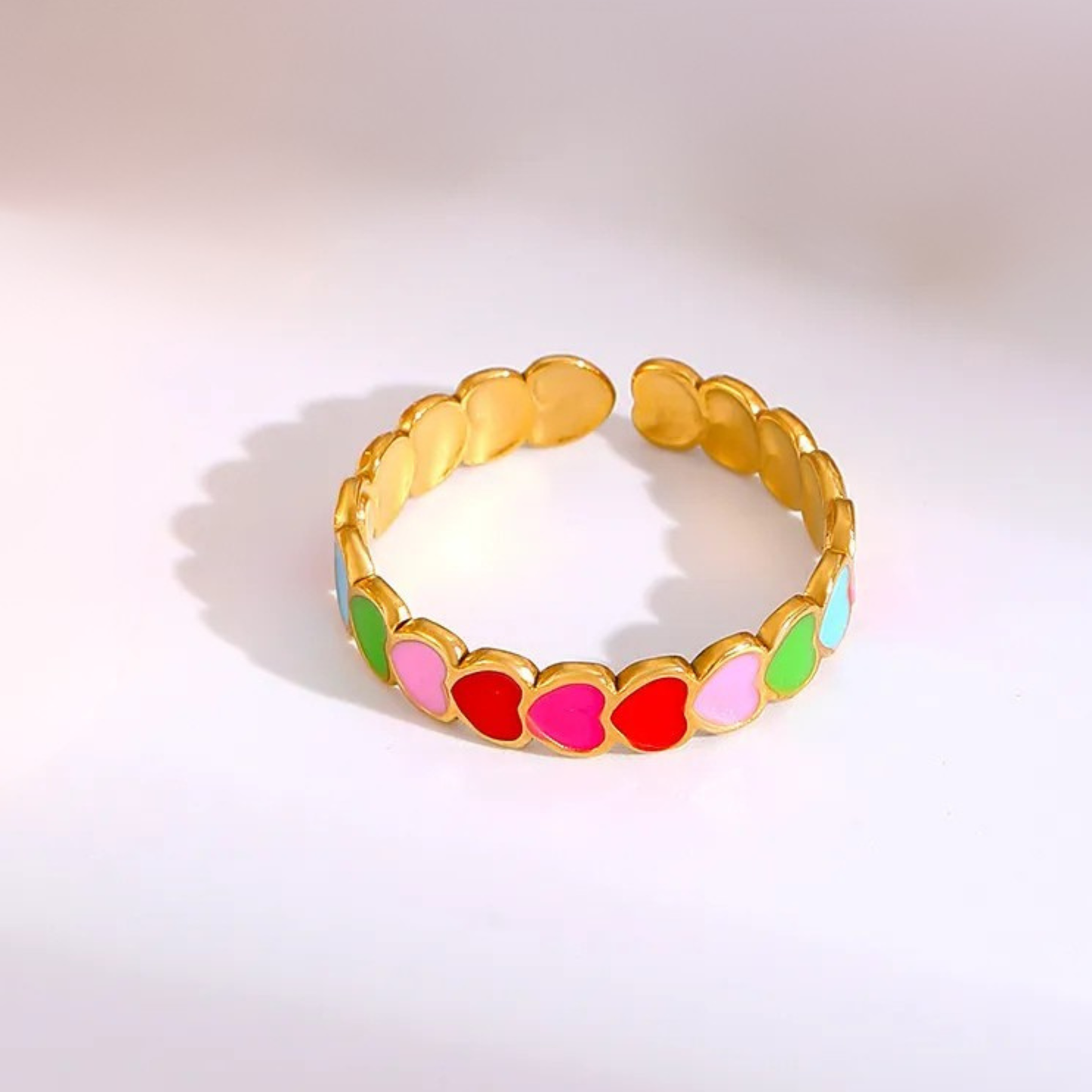 Gold bracelet with colorful heart-shaped beads on a light gray background