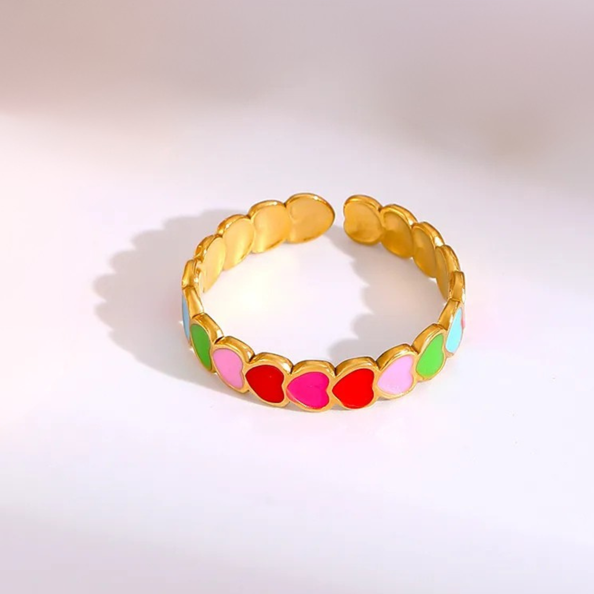 Gold bracelet with colorful heart-shaped beads on a light gray background