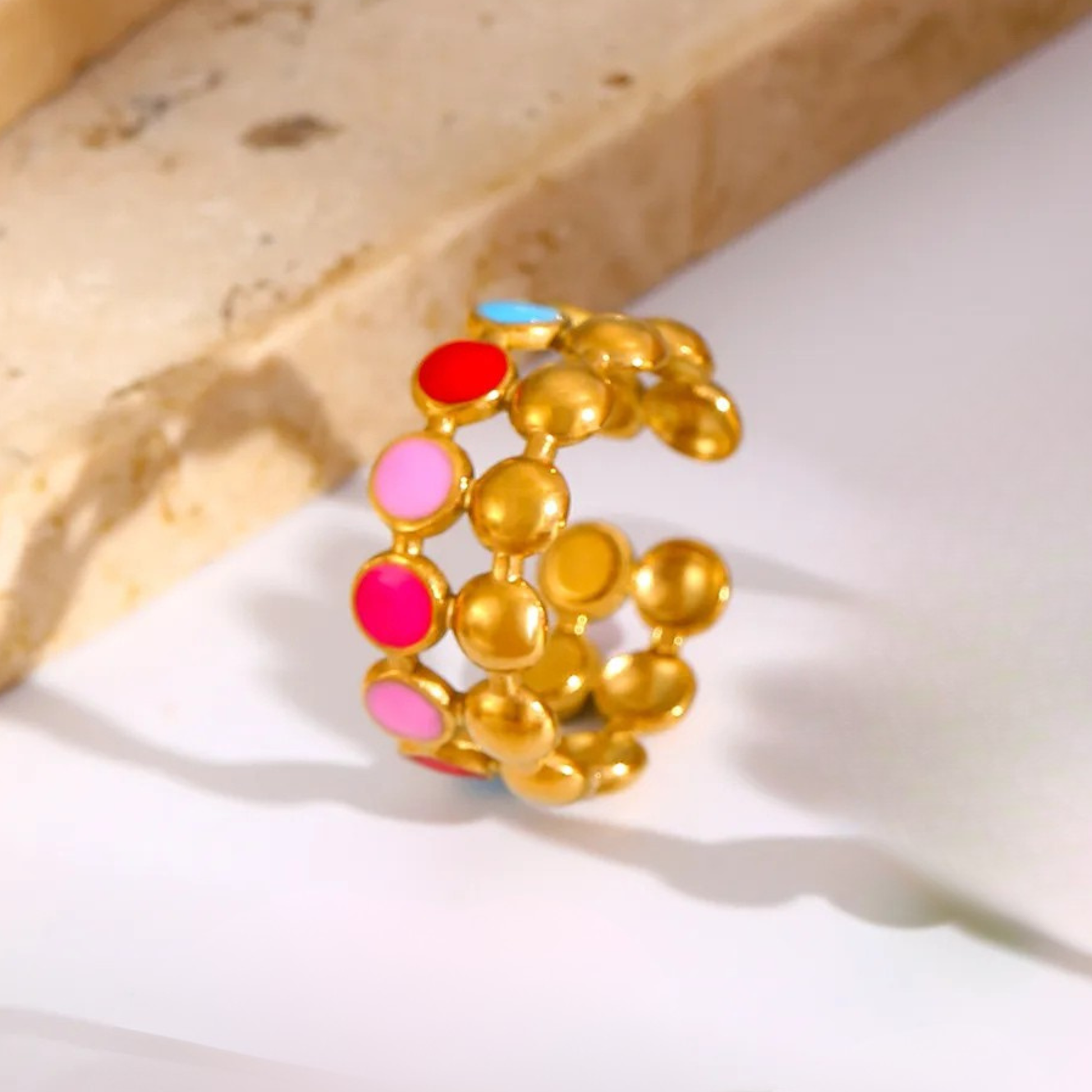 Gold ring with colorful beads on a light background