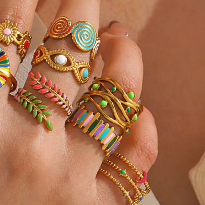 Close-up of a hand wearing multiple colorful rings on a neutral background