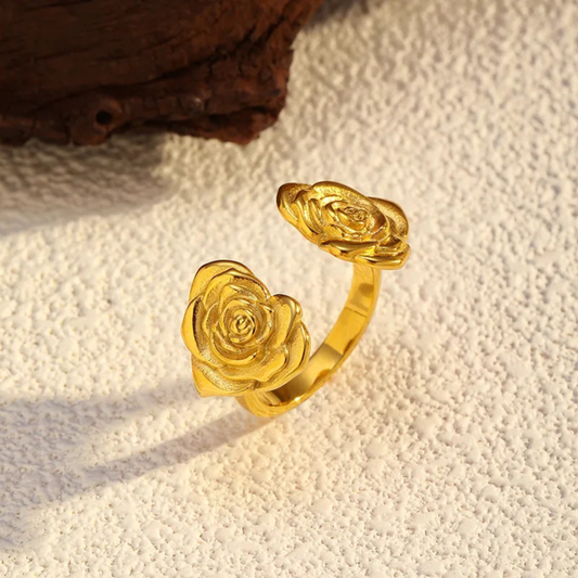 Gold rose-shaped ring on a textured beige surface