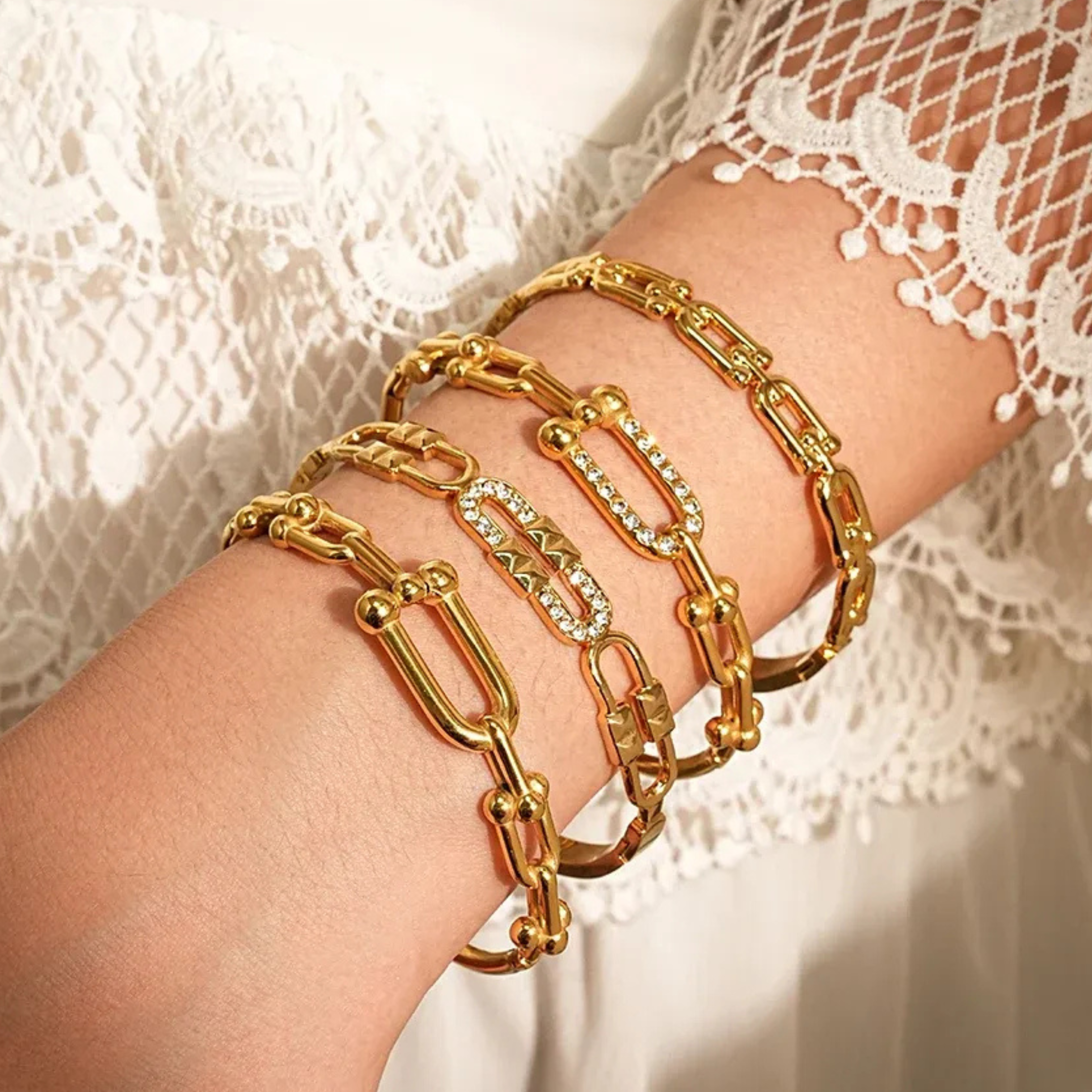 Gold chain bracelets on a wrist with a lace background