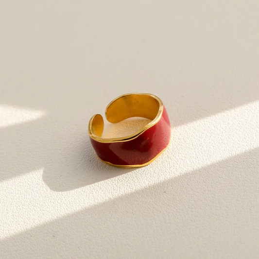 Gold and red ring on a light beige background