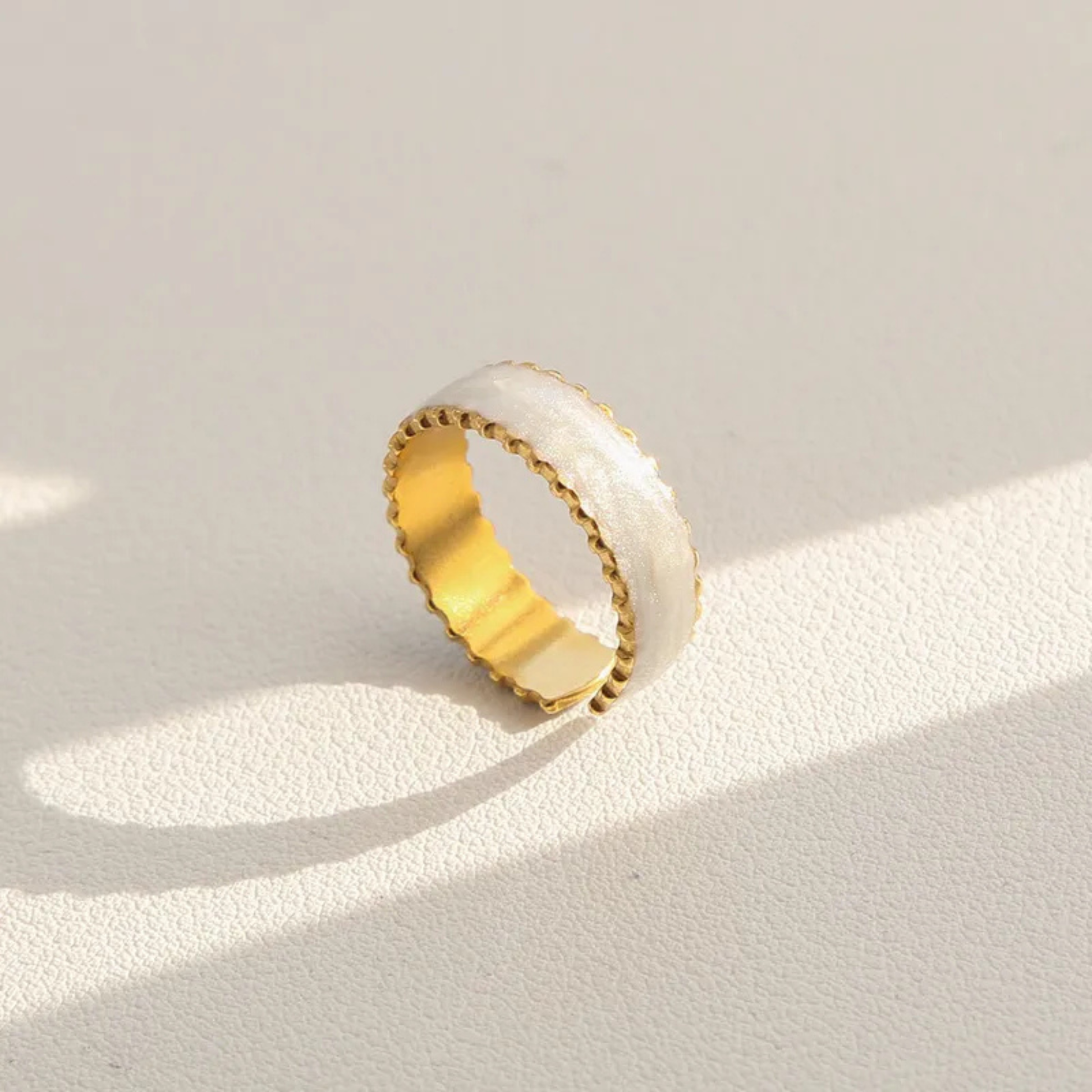 Gold and white ring on a light beige background