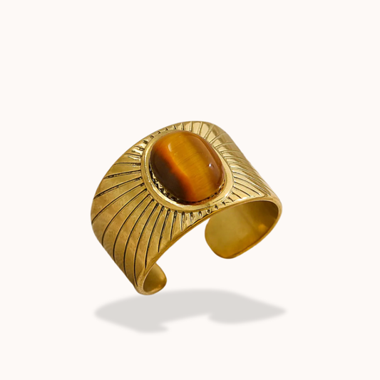 Gold bracelet with a brown gemstone on a white background