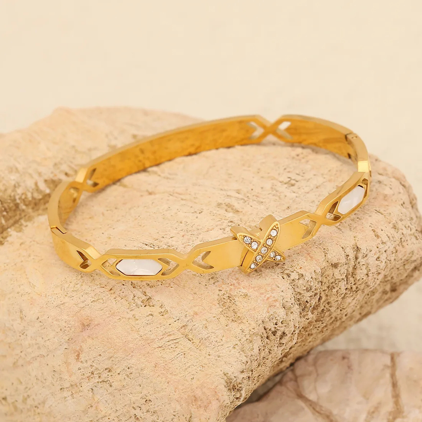 Gold bracelet with geometric design on a textured beige surface