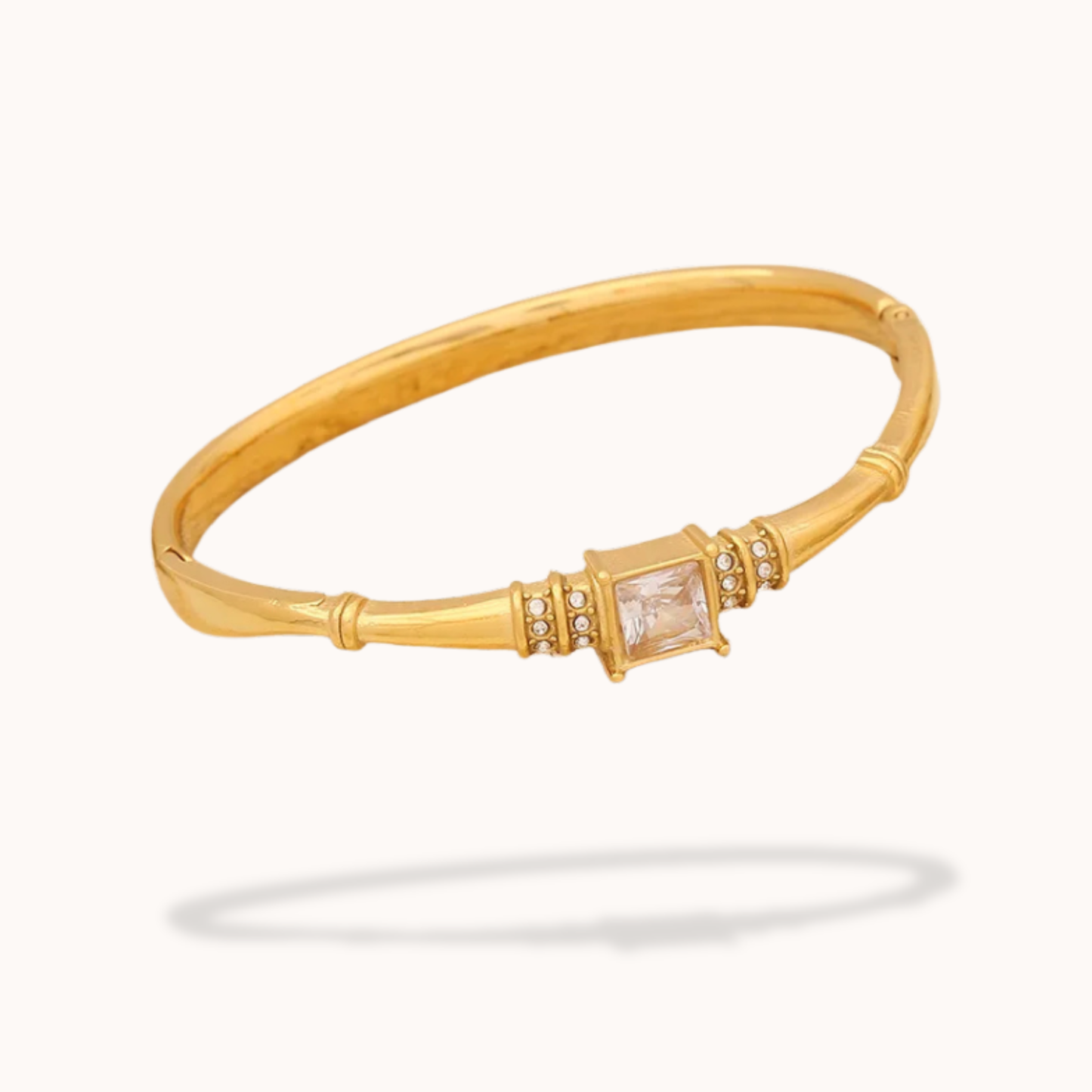 Gold bracelet with a central gemstone on a white background
