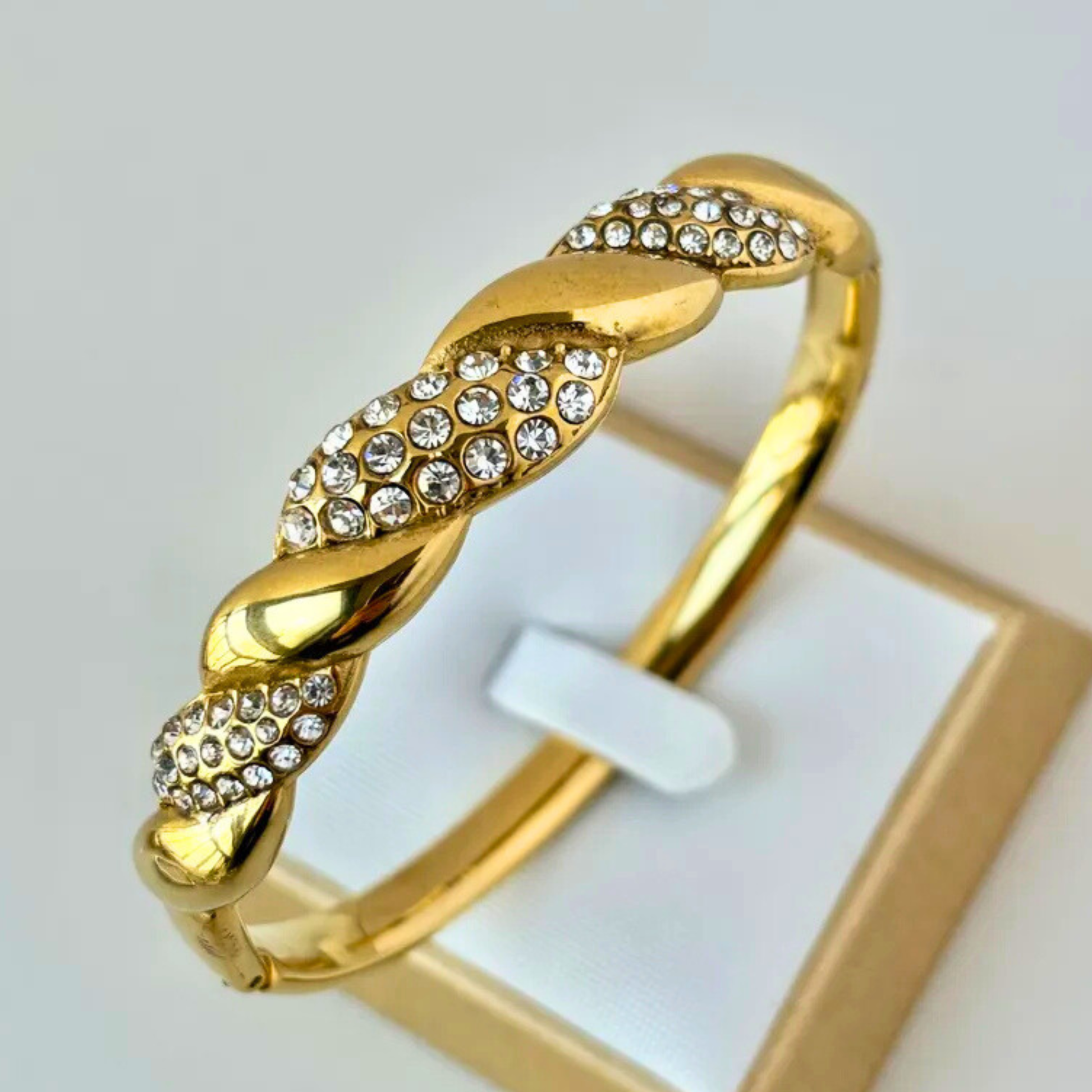 Gold bracelet with crystal embellishments on a light gray background