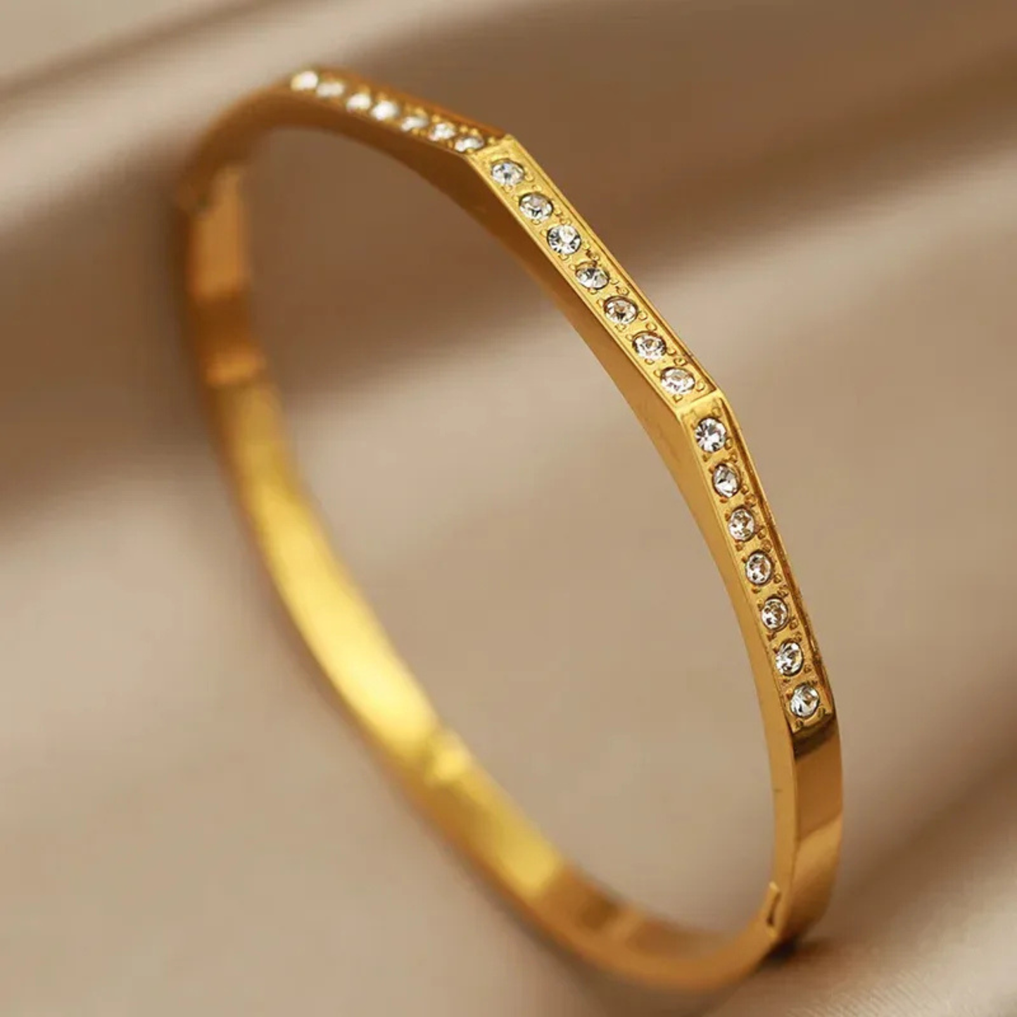 Gold bracelet with small diamonds on a beige background