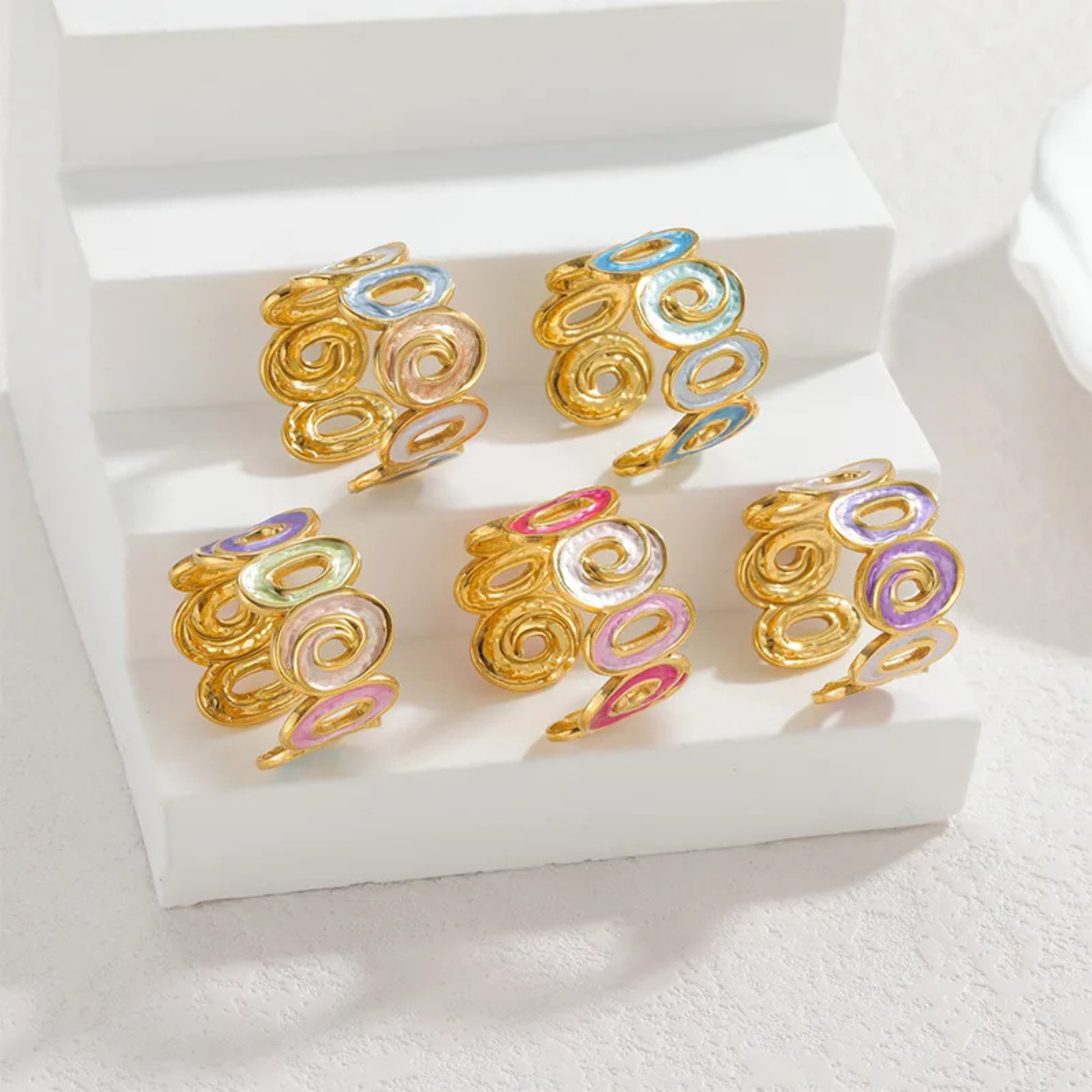 Gold earrings with colorful circular designs on a white surface