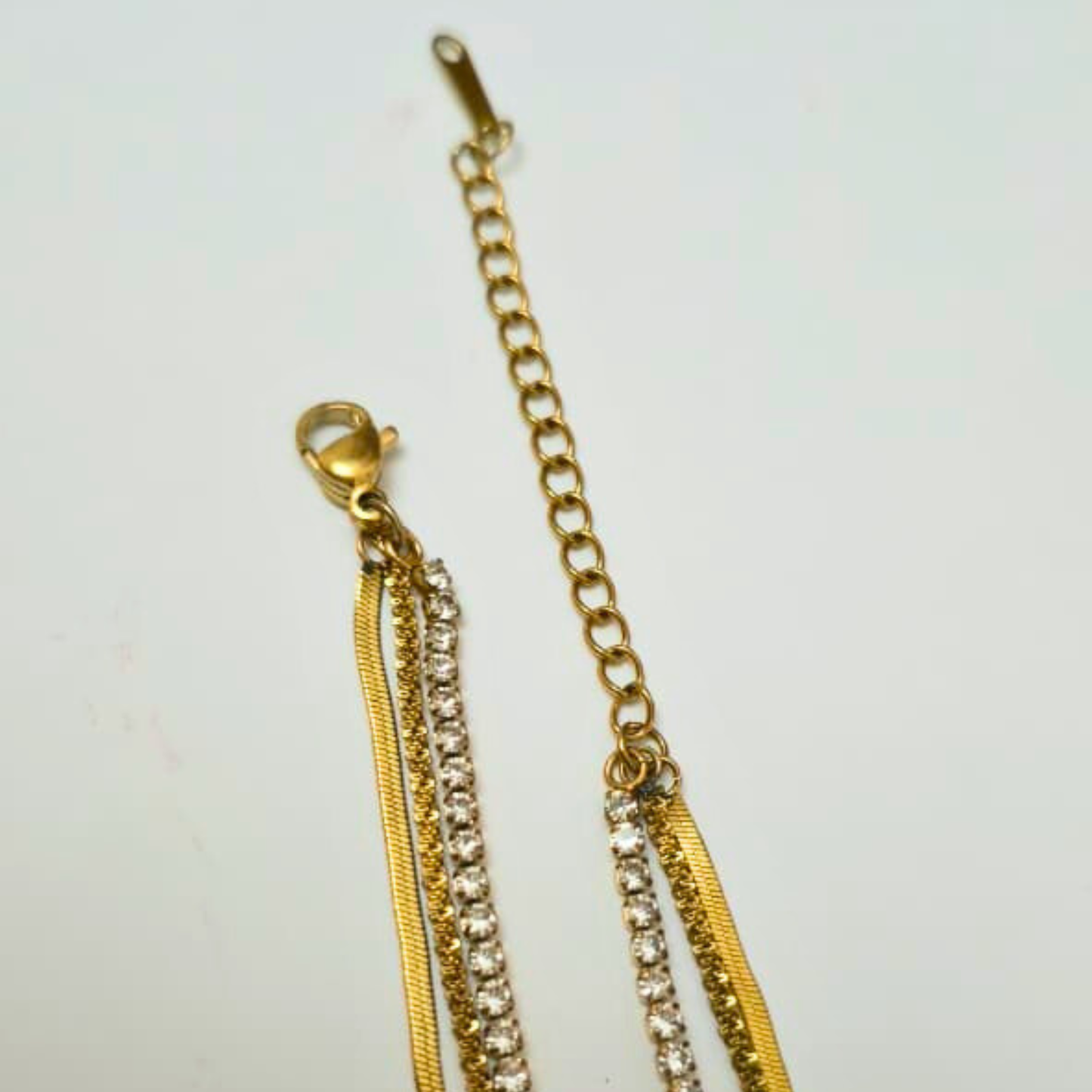 Gold chain with rhinestone accents on a light gray background