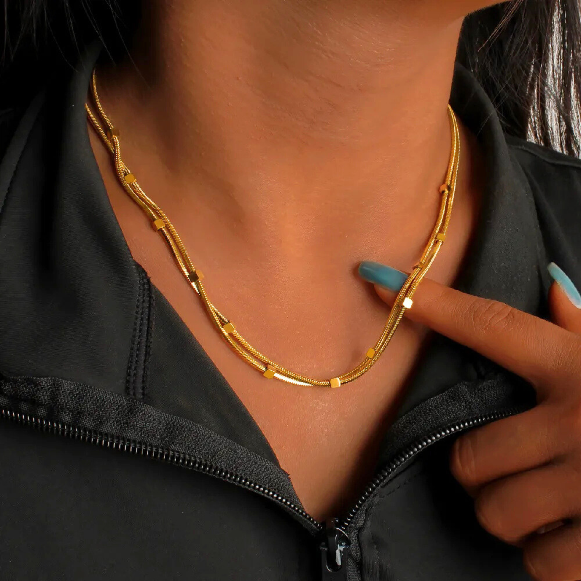 Gold necklace worn by a person with a black jacket