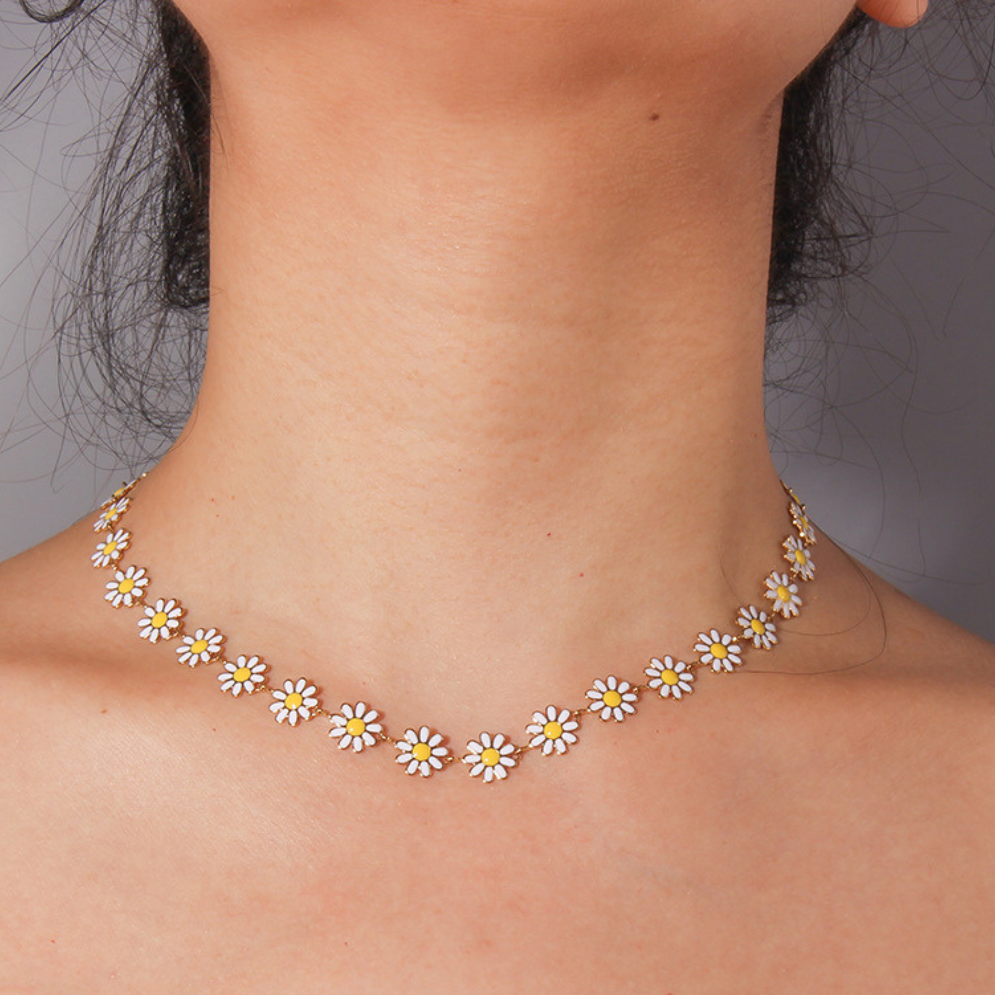 Necklace with daisy flower pendants on a person against a neutral background