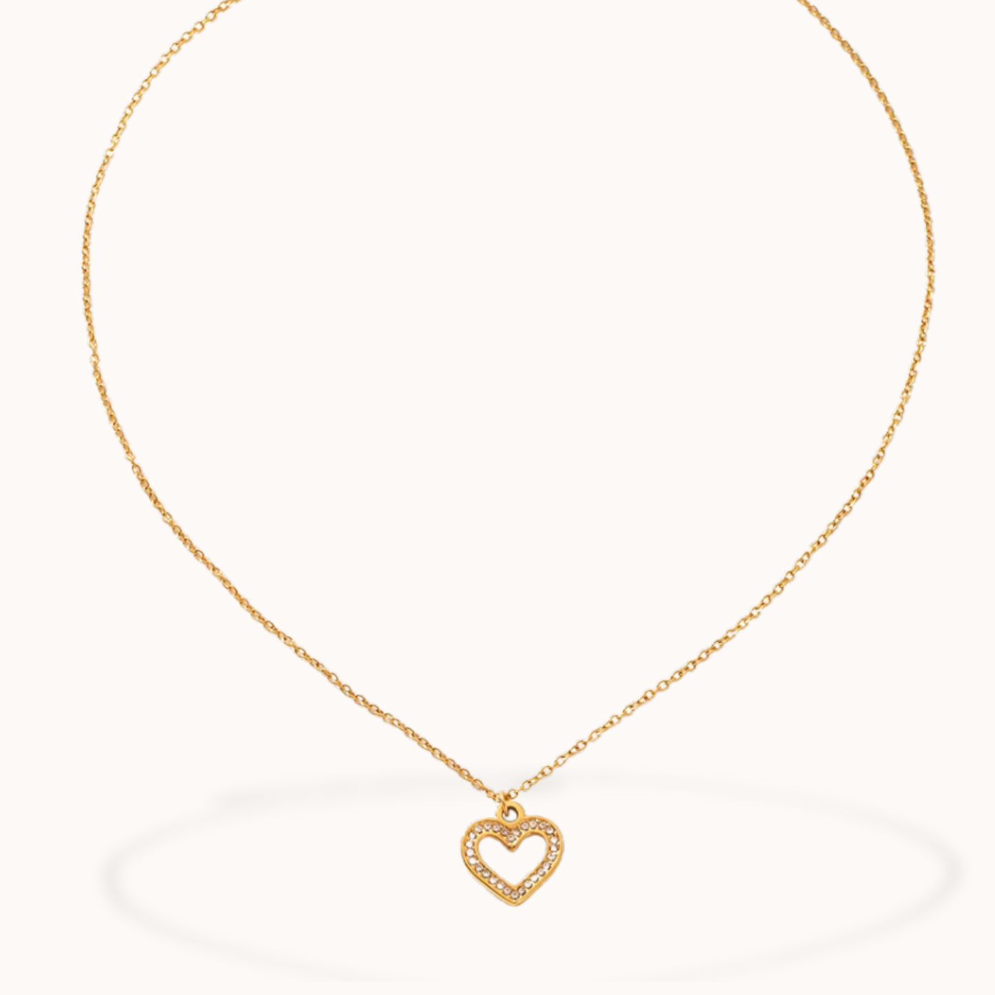 Gold necklace with a heart-shaped pendant on a white background